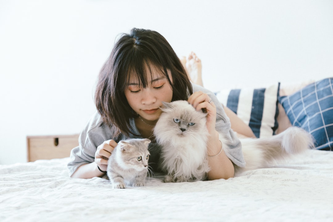 A smiling person cradling a small kitten in a home.